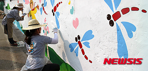 【영동=뉴시스】김기준 기자 = 충북 영동군 양산면 죽산리의 허름하고 잡스러운 주택 담장에 지난 20일 군과 충북 광역 정신건강증진센터 직원들이 화사한 꽃과 허수아비·잠자리 등 가을 들녘 풍경을 그려 넣고 있다. 2015.10.21.(사진=영동군청 제공) photo@newsis.com