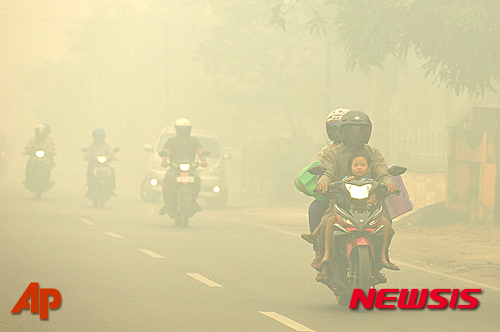 【 보르네오=AP/뉴시스】인도네시아 보르네오 시민들이 27일 연무로 자욱한 시내에서 오토바이를 타고 지나고 있다. 2015.10.27&nbsp; 