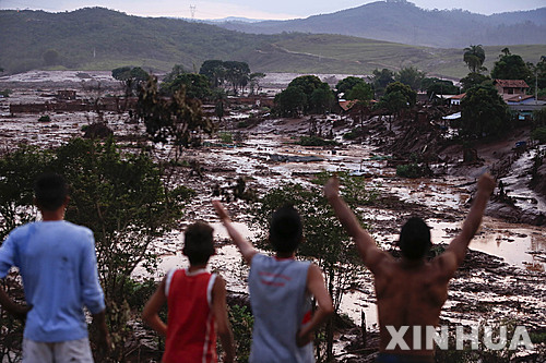 [벤토 로드리게스=신화/뉴시스]브라질 남동부 미나스 헤라이스주 벤토 로드리게스에서 2015년 11월5일 광산지역 댐이 붕괴되면서 일대가 물과 진흙에 잠긴 모습을 주민들이 고지대에서 바라보고 있다. 영국 고등법원은 14일 브라질 최악의 환경 재앙으로 꼽히는 2015년의 댐 붕괴 사고에 대해 세계적인 광산 대기업 BHP 그룹에 책임이 있다고 판결했다. 2025.11.14. 