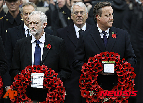 【런던=AP/뉴시스】영국 현충일인 8일 데이비드 캐머런 총리(오른쪽)와 제일 야당인 노동당의 제리미 코빈 당수가 여왕이 참석한 연례 행사에 추모 화환을 하나씩 들고 참전용사의 행진을 보고 있다. 뒤쪽에 노동당의 토니 블레어 전 총리, 보수당의 존 메이저 전 총리가 서 있다. 화환의 꽃은 영국 顯忠의 꽃인 붉은 양귀비로 이날이 아니더라도 총리 등의 옷깃에서 가끔 볼 수 있다. 2015. 11. 8.&nbsp;&nbsp; 