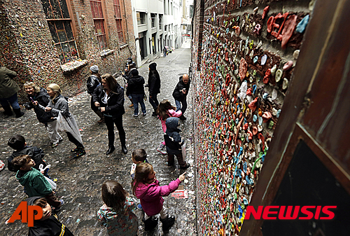 【 시애틀=AP/뉴시스】미국 워싱턴주의 시애틀에 있는 명물 '껌 벽' 앞에서 9일(현지시간) 관광객과 아이들이 구경하고 있다. 갖가지 색깔의 씹다만 껌들이 붙어 있는 이 벽은 곧 철거될 예정이다. 2015.11.10 