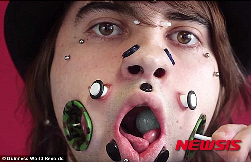  【서울=뉴시스】조엘 미글러라는 이름의 독일의 한 청년은 얼굴에 무려 11개의 피어싱을 해 2015년 세계 기네스북에 올랐다. 사진은 조엘이 볼에 난 구멍을 통해 막대사탕을 먹는 모습이다.(사진출처: 데일리메일) 2015.11.13. 