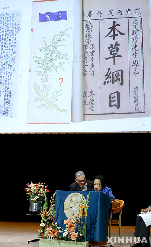 【 스톡홀름= 신화/뉴시스】올해 노벨 생리의학상 수상자인 중국의 투유유 교수가 7일(현지시간) 스웨덴 스톡홀름 카롤린스카연구소에서 강연하는 동안 무대 위 화면에 전통약초학 연구서 '본초강목'의 표지가 비춰지고 있다. 2015.12.08 