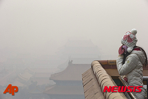 【베이징=AP/뉴시스】미세 먼지의 대기 오염으로 스모그가 잔뜩 낀 중국 수도에서 한 여성이 마스크를 만지고 있다. 베이징은 이날까지 나흘 연속 스모그 적색 경고가 발령됐다. 석탄 난방과 습기가 이 불건강한 연무의 주 원인이다. 2015. 12. 22.