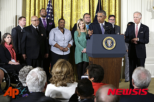 【워싱턴=AP/뉴시스】버락 오바마 미국 대통령이 5일(현지시간) 워싱턴 백악관 이스트룸에서 총기규제 행정명령의 필요성을 설명하고 있다. 오바마 대통령과 함께 연단에 선 사람들은 총기 사고를 당하거나 사랑하는 사람을 잃은 아픔을 겪은 사람들이다. 연단 아래서도 총기 사고 피해자들과 총기 규제 운동가들이 대통령의 연설을 지켜보고 있다. 2016.01.06