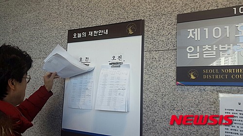 【서울=뉴시스】이승주 기자 = 18일 오전 서울 북부지방법원 제 101호 입찰법정 앞. 한 남성이 이날 경매에 오른 물건을 살피고 있다.