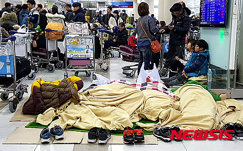 【제주=뉴시스】조명규 기자 = 24일 아침 제주공항 내 한 항공사의 발권데스크 앞에서 많은 체류객들이 비행기 재운항을 기다리고 있다. 이날 제주공항은 제설작업으로 인해 정오까지 활주로를 폐쇄한다고 밝혔다. 2016.1.24  mkcho@newsis.com