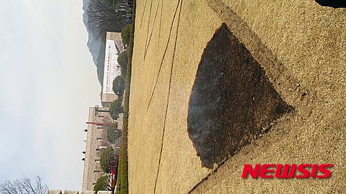 【서울=뉴시스】박현주 기자 = 18일 국립현대미술관 과천관에서 설치미술가 김구림씨가 미술관 잔디밭에 불을 질러 8m 삼각형 무늬가 검게 붙라고 있다.