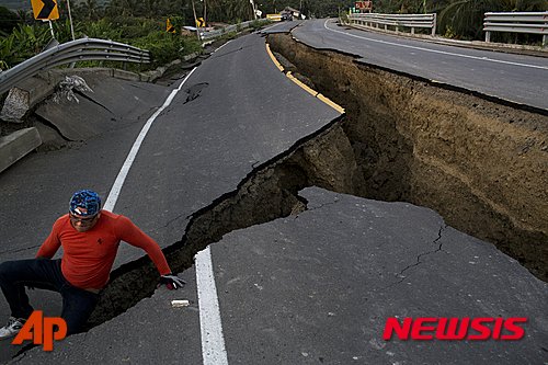 【차크라스=AP/뉴시스】에콰도르 차크라스에서 19일(현지시간) 한 주민이 규모 7.8 지진으로 깊게 갈라진 고속도로 틈새에 들어갔다 나오고 있다. 206.04.20 