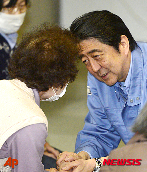【미나미아소(구마모토 현)=AP/뉴시스】23일 아베 신조(安倍晋三) 일본 총리가 연쇄 지진으로 큰 피해를 입은 구마모토(熊本)현 미나미아소(南阿蘇)에 위치한 한 대피소를 방문해 한 이재민과 손을 맞잡고 대화하고 있다. 그는 이번 방문에서 무릎을 꿇고 이재민들의 손을 맞잡는 등 정중한 태도로 이재민들의 호소에 귀를 기울였다. 2016.04.23.