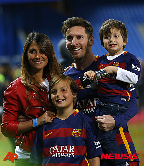 Barcelona's Lionel Messi, carrying his son, posses for a photo with his wife Antonella Roccuzzo as they celebrate after winning the final of the Copa del Rey soccer match between FC Barcelona and Sevilla FC at the Vicente Calderon stadium in Madrid, Sunday, May 22, 2016. Barcelona won 2-0 (AP Photo/Francisco Seco)