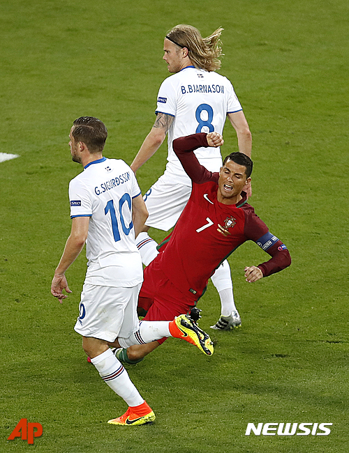 Portugal's Cristiano Ronaldo, center, falls between Iceland's Gylfi Sigurdsson, left, and Birkir Bjarnason during the Euro 2016 Group F soccer match between Portugal and Iceland at the Geoffroy Guichard stadium in Saint-Etienne, France, Tuesday, June 14, 2016. (AP Photo/Michael Sohn)