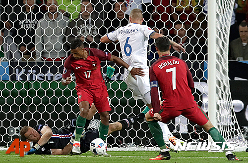 Portugal's Nani, 2nd left, challenges Iceland goalkeeper Hannes Halldorsson, on the ground, during the Euro 2016 Group F soccer match between Portugal and Iceland at the Geoffroy Guichard stadium in Saint-Etienne, France, Tuesday, June 14, 2016. (AP Photo/Pavel Golovkin)