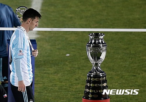 FILE - In this July 4, 2015 file photo, Argentina's Lionel Messi walks next to the Copa America trophy during the Copa America final soccer match at the National Stadium in Santiago, Chile. Messi's shocking decision to stop playing for Argentina could further hurt his already tarnished legacy with his national team. If Messi sticks to his announcement, made in the heat-of-the-moment shortly after Argentina's penalty shootout loss to Chile in Sunday's Copa America final on June 26, 2016, Argentina will be left dwelling on the fact that it was not able to win any significant title while having one of the best players of all time. (AP Photo/Silvia Izquierdo, File)