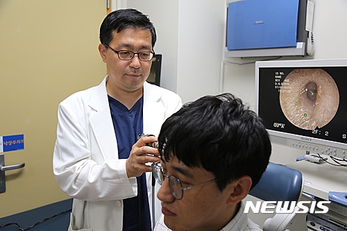 【서울=뉴시스】장마철 스마트폰으로 이어폰을 장시간 귀에 꽂으면 외이도염에 걸릴 위험성이 높다는 지적이 제기됐다. 자료사진은 문석균 중앙대병원 이비인후과 교수 외이도염 환자를 진료하는 모습. (사진: 중앙대병원 제공) 2016.07.04