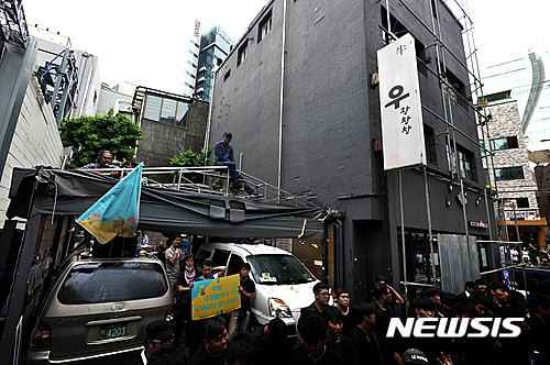 【서울=뉴시스】 박문호 기자 = 7일 오전 서울 신사동 가로수길 힙합듀오 '리쌍'이 소유한 건물에서 맘편히장사하고픈상인모임(맘상모) 등 시민단체 회원들이 임대 계약 문제로 마찰을 빚었던 곱창집 '우장창창'이 법원의 퇴거 강제집행을 막고 있다.&nbsp; 서 씨는 2010년 11월 현재 건물 1층에 곱창집을 개업했다. 1년 반 만에 건물주가 리쌍으로 바뀌며 서 씨는 리쌍 측으로부터 보증금과 1억8000만 원을 받고 건물 1층 주차장과 지하를 용도변경해 임대하는 조건으로 합의했다. 법원은 임대계약 종료 6개월에서 1개월 사이 건물주에게 계약 갱신 요구를 하지 않았다는 이유로 퇴거 명령을 내리고 지난 5월 30일 2차 퇴거명령 계고장의 기한이 지나 이날 새벽 6시께 강제집행을 진행했으나 가게에서 숙식하며 집행에 대비하던 서 씨와 맘상모 등 시민단체 회원들이 경비용역과 충돌해 10시께 강제집행을 멈추고 용역을 철수했다. 맘상모는 임대 계약을 일방적으로 해지하는 건물주에 맞서 상가 세입자들이 결성한 단체다. 2016.07.07.&nbsp; go2@newsis.com