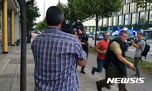 【뮌헨=AP/뉴시스】22일(현지시간) 총격 사건이 발생한 독일 뮌헨의 올림피아 쇼핑센터 인근에서 독일 무장경찰들이 언론사 카메라 기자 앞을 뛰어 지나가고 있다. 뮌헨 경찰은 사망자 수를 밝히지 않은 채 많은 사망자가 발생한 것으로 보인다고 말했다. 2016.7.23