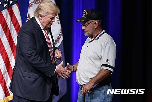 【애슈번=AP/뉴시스】미국 공화당 대선 후보 도널드 트럼프가 2일(현지시간) 버지니아주 애슈번 유세에서 자신에게 퍼플 하프 훈장(부상당한 군인에게 수여하는 훈장)을 선물한 재향군인 루이스 도르프만과 악수하고 있다. 2016.8.3. 