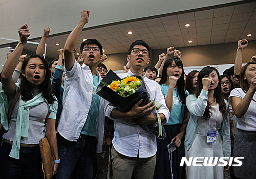 【홍콩=AP/뉴시스】지난 2014년 홍콩 민주화 시위를 이끈 지도자 중 한 사람이 네이선 로(가운데)가 5일 입법회 선거 개표결과 당선이 확정된 후 축하 꽃다발을 안고 있다. 왼쪽에 서 있는 사람은 네이선 로와 함께 시위를 이끌었던 조슈아 웡이다. 2016.09.05