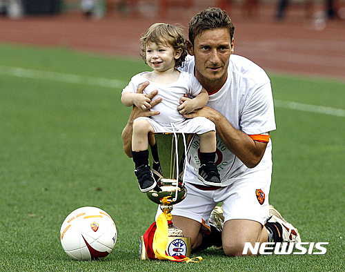 FILE - In this May 27, 2007 file photo, Roma's Francesco Totti poses for photographers with his son Cristian and the Italian Cup trophy at the end of the Italian top league soccer match between AS Roma and Messina at Rome's Olympic Stadium. Totti celebrates his 40th birthday on Tuesday, Sept. 27, 2016,  but is showing no signs of slowing down and indeed seems to have found a new lease of life. He may not be Roma's 'Golden Boy' anymore but he is still very much 'the King of Rome.'  (AP Photo/Alessandra Tarantino)