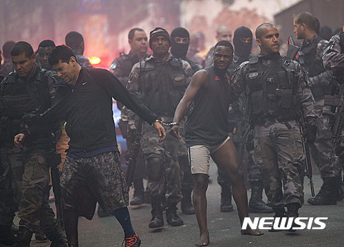 【리우데자네이루(브라질)=AP/뉴시스】 브라질 경찰이 10일 리우데자네이루 시내 빈민가인 파바오 파바오지노 지역에서 대규모 작전을 펼친 뒤 사람들을 수갑을 채워 연행하고 있다. 이날 경찰은 이 지역에서 총격전을 펼치며 마약단속에 나섰고 보안군이 한 때 증원되었다. 2016.10.11