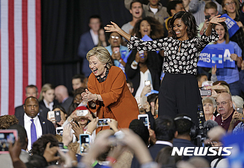 【윈스턴-살렘=AP/뉴시스】미국 민주당 대선후보인 힐러리 클린턴과 미셸 오바마 여사가 27일(현지시간) 노스캐롤라이나주 윈스턴-살렘에서 열린 공동유세에서 지지자들의 환호에 답례하고 있다. 2016.10.28
