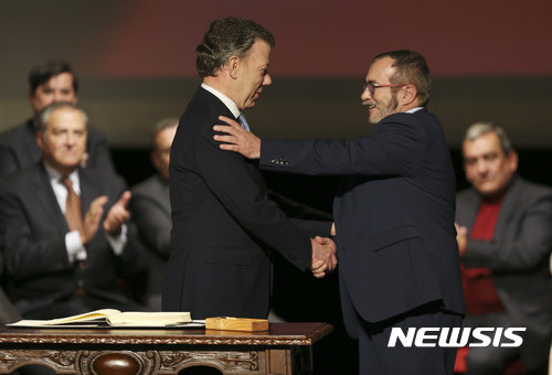 【보고타=AP/뉴시스】콜롬비아 최대 반군인 콜롬비아무장혁명군(FARC)이 무기 인도 절차를 완료했다고 유엔이 26일 보도했다. 사진은 후안 마누엘 산토스 콜롬비아 대통령(왼쪽)과 FARC 지도자 로드리고 론도뇨가 지난해 11월 24일(현지시간) 보고타에서 평화협상 수정안에 서명한 후 서로 악수하고 있는 모습.&nbsp; 2016.11.25