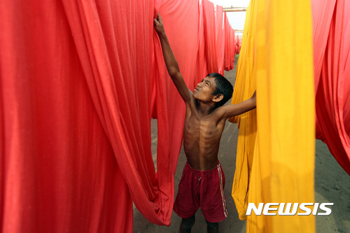 【AP/뉴시스】2012년 12월 자료 사진으로, 방글라데시 수도 교외에서 한 소년이 의복 염색 공장에서 일하고 있다. 7일 영국의 한 보고서는 이곳에서 1주 64시간 일하는 아동들이 수천 명에 달한다고 말했다. 2016. 12. 7.