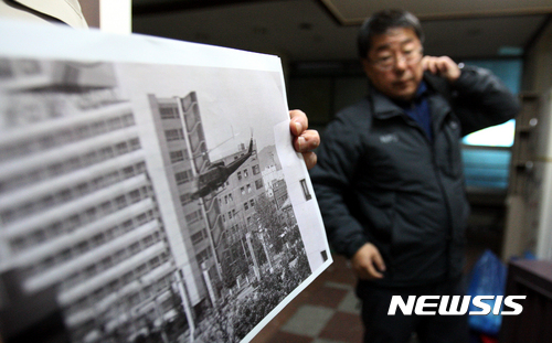 【광주=뉴시스】신대희 기자 = 13일 오후 광주 동구 금남로 1가 1번지 전일빌딩 3층 윤동주문학관 사무실에서 김동환 국립과학수사연구원 총기안전실장이 5·18 민주화운동 당시 계엄군이 쏜 것으로 추정되는 총탄 흔적에 대한 조사를 벌인 뒤 헬기 사진을 바라보고 있다. 2016.12.13.&nbsp; sdhdream@newsis.com