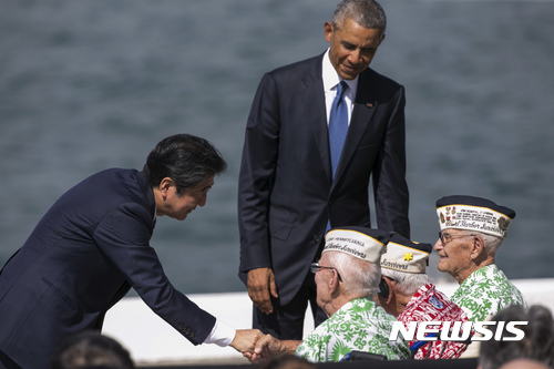 [진주만=AP/뉴시스]아베 신조 전 일본 총리가 지난 2016년 12월 27일(현지 시간) 미국 하와이 호놀룰루 인근 히캄 기지 필로 부두에서 연설한 후 일본군의 진주만 공습에서 살아남은 노병들과 악수하고 있다. 2026.03.20 