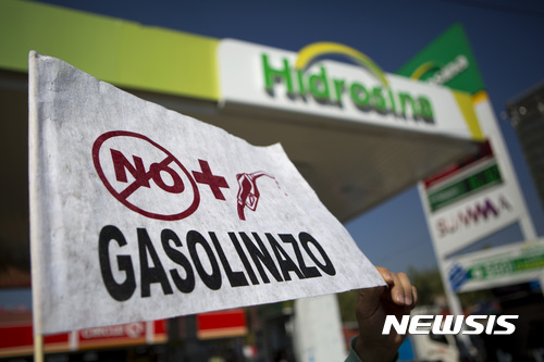 【멕시코시티 = AP/뉴시스】 멕시코 수도 멕시코시티의 중심가에 있는 오래된 주유소 앞에서 2일(현지시간) 시위대가 "더이상의 유가인상 금지" 펼침막을 들고 시위를 벌이고 있다. 연말이자 주말인 31일부터 20%나 인상된 가솔린 가격은 정부의 유가규제 철폐와 민영화 계획의 여파이다. 유가폭등으로 인해 전국적으로 고속도로와 주유소 점거 등 항의시위가 벌어지고 있다. 2017.01.03    
