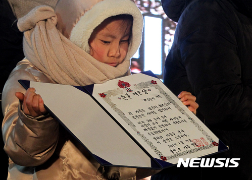 【제주=뉴시스】우장호 기자 = 14일 오후 제주시청 종합민원실 앞 도로에서 박근혜 정권 퇴진 제주행동 주최로 제주지역 13차 촛불집회가 열렸다. 이날 집회에서는 13차 촛불집회가 진행되는 동안 한번도 빠짐없이 집회에 참석한 강슬아 어린이 가족이 촛불 개근상을 받았다. 2017.01.14.  woo1223@newsis.com