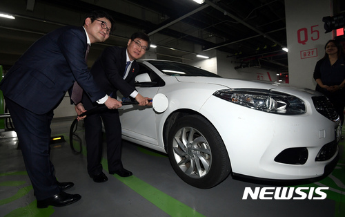 【서울=뉴시스】이영환 기자 = 조경규(가운데) 환경부 장관과 김종인(왼쪽) 롯데마트 대표가 17일 오후 서울 송파구 롯데월드타워에서 열린 2017년 전기자동차 충전 인프라 확산 캠페인 발대식에서 업무협약을 마치고 전기차와 충전 시연을 하고 있다.  롯데마트는 '업무협약을 통해 전기차 충전기 부지를 무상으로 제공하며 올 해 안에 전 점에 전기차 충전기를 설치할 계획'이라고 전했다. 2017.01.17.   20hwan@newsis.com