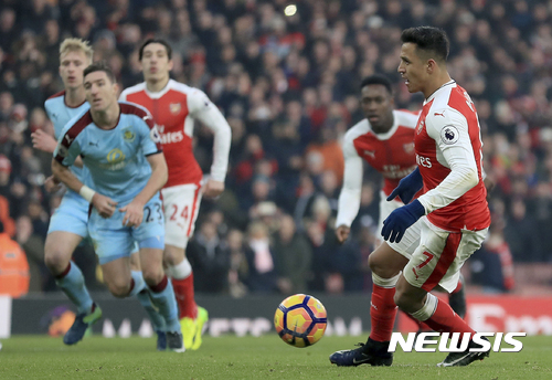 Arsenal's Alexis Sanchez, right, scores a penalty at the end of the match against Burnley, during their English Premier League soccer match at The Emirates Stadium in London, Sunday Jan. 22, 2017. (Mike Egerton/PA via AP)