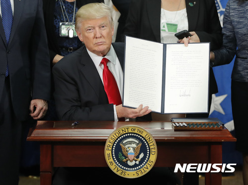 【 워싱턴=AP/뉴시스】도널드 트럼프 미국 대통령이 25일(현지시간) 워싱턴 국토안보부에서 멕시코와의 국경지대에 장벽을 건설하는 행정명령에 서명한 후 들어보이고 있다. 2017.01.26 