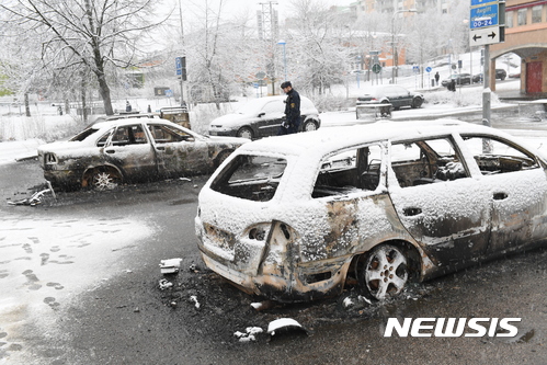 【 린케비=AP/뉴시스】스웨덴 경찰이 21일(현지시간) 스톡홀름 외곽 이민자 밀집지역인 린케비에서 불에 탄 스용차를 조사하고 있다. 스웨덴 경찰은 이날 스톡홀름 외곽 이민자 거주지에서 경찰의 범죄자 검거 과정 중 경찰과 주민 간 충돌이 격화된 폭력사태에 대해 수사 중이다. 2017.02.22 