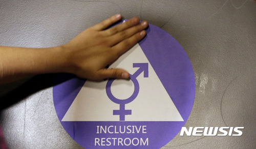 【AP/뉴시스】 = 지난 해 5월 17일 버락 오바마 대통령의 행정 지침에 따라서 성전환 학생들의 현재 성에 따른 시설 사용이 허가된 후 시애틀시의 네이선 헤일 고교의 화장실에서 가졌던 기념행사에서 성적 소수자 보호 스티커가 부착되고 있다. 트럼프 정부는 앞으로 이를 다시 폐지하고 출생증명서의 성에 따르도록 할 것이라고 백악관 대변인이 밝혔다.