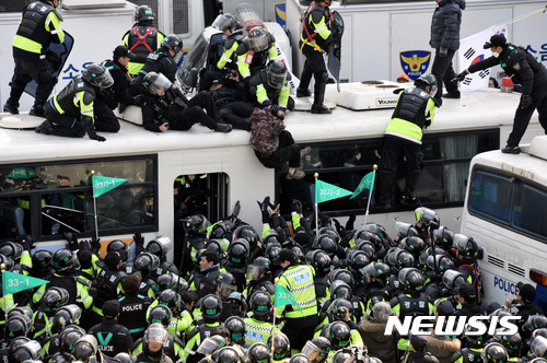 [서울=뉴시스]홍찬선 기자 = 헌재가 박근혜 대통령의 탄핵을 인용을 결정한 지난 2017년 3월10일 오후 서울 종로구 헌법재판소 앞 도로에서 탄핵 인용에 반대하는 집회가 열리고 있는 모습. 버스 위로 올라간 한 시민이 경찰과 몸싸움을 벌이며 버스 지붕 아래로 떨어지고 있다. 2017.03.10.&nbsp; mania@newsis.com