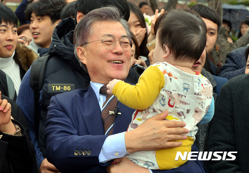 【광주=뉴시스】류형근 기자 = 더불어민주당 문재인 전 대표가 20일 오후 광주 북구 전남대학교 후문에서 대통령 선거 홍보 영상을 촬영하고 있는 가운데 어린이를 품에 안고 바라보고 있다. 2017.03.20.&nbsp;&nbsp;&nbsp; hgryu77@newsis.com