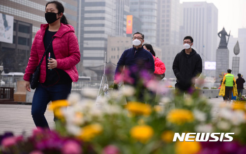 【서울=뉴시스】추상철 기자 = 미세먼지 농도가 '나쁨'단계를 보인 28일 오전 서울 종로구 광화문광장에서 마스크를 쓴 관광객이 봄꽃이 심어진 화단을 지나고 있다. 2017.03.28. scchoo@newsis.com