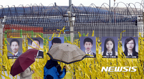 【목포=뉴시스】류형근 기자 = 인양된 세월호 육상거치를 앞둔 5일 오전 전남 목포시 목포신항에서 추모객들이 철망에 걸려 있는 미수습자 9명의 사진을 보고 있다. 2017.04.05.  hgryu77@newsis.com