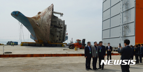 【목포=뉴시스】류형근 기자 = 7일 오후 전남 목포신항을 찾은 한 정당 당직자들이 '세월호가 거치된 반잠수식 선박 앞에서 기념촬영'을 하고 있다. 옆에서 이를 지켜본 유족들은 불쾌한 심기를 드러냈다. 2017.04.07. photo@newsis.com