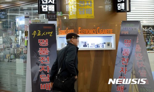 【서울=뉴시스】고범준 기자 = 식품의약품안전처가 국내 유통되는 국산 및 외산 담배 5종과 전자담배 35종에 대한 유해 성분 분석 결과를 발표한 11일 오후 서울 중구의 한 쇼핑센터 전자담배 판매점 앞으로 시민들이 지나가고 있다.&nbsp;&nbsp; 식약처 발표 결과에 따르면 제품에 따라 전자담배의 니코틴 액상이 가열과 산화를 거치면 특정 발암물질의 함량이 최대 19배 증가하는 것으로 드러났다. 그러나 전자담배 발암물질은 궐련담배의 연기에 포함된 발암물질보다는 농도가 낮은 것으로 나타나 전자담배가 궐련담배보다는 유해성이 낮은 것으로 조사됐다. 2017.04.11.&nbsp;&nbsp; bjko@newsis.com