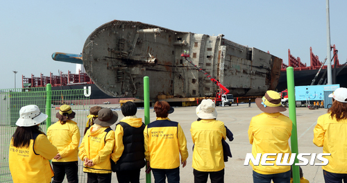 【목포=뉴시스】류형근 기자 = 13일 오전 전남 목포시 목포신항만에서 코리아쌀베지 직원들이 크레인을 이용해 육상거치된 세월호 세척과 불순물 제거 작업을 하고 있는 가운데 유가족들이 지켜보고 있다. 해수부는 세척과 방역, 안정장비 설치 등의 작업을 한 뒤 미수습자 9명을 수색할 방침이다. 2017.04.13.    hgryu77@newsis.com