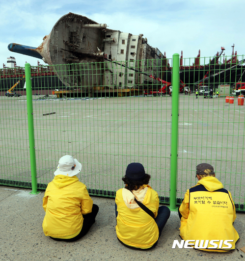 【목포=뉴시스】류형근 기자 = 14일 오전 전남 목포시 목포신항만에서 코리아쌀베지 직원들이 크레인을 타고 고압 세척기계를 이용해 세월호 선체 세척과 불순물 제거 작업을 하고 있는 가운데 유가족들이 지켜보고 있다. 해수부는 세척과 방역, 안정장비 설치 등의 작업을 한 뒤 미수습자 9명을 수색할 방침이다. 2017.04.14.  hgryu77@newsis.com