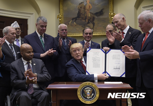 【워싱턴=AP/뉴시스】도널드 트럼프 미국 대통령이 19일(현지시간) 워싱턴 백악관에서 전역 군인 지원 확대 행정명령에 서명한 이후 들어보이고 있다. 2017.04.20&nbsp; 