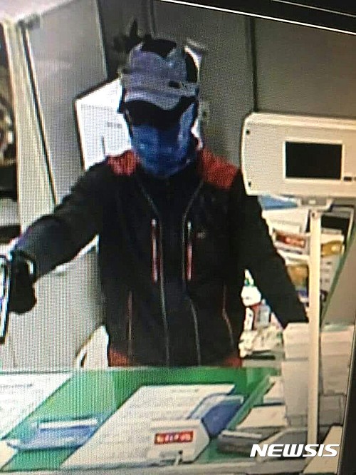 【경산=뉴시스】김덕용 기자 = 20일 오전 11시57분께 경산시 자인농협에서 발생한 총기강도사건 당시의 CCTV 화면. 강도 용의자가 권총을 들고 창구직원에게 현금을 자루에 담을 것을 요구하고 있다. 경찰은 범인의 키가 175cm~180cm사이로 추정하고 있다. 2017. 04. 20. (사진=페이스북 실시간경산 캡쳐) photo@newsis.com