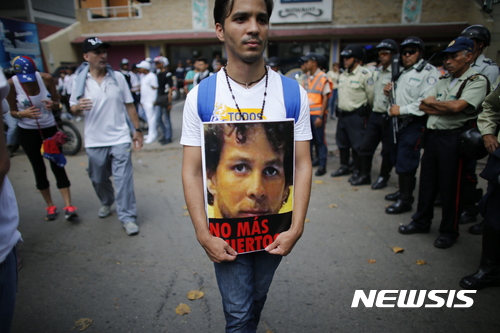 【카라카스(베네수엘라) = AP/뉴시스】 = 22일의 침묵 시위에서 한 청년이 지난 20일 바르키시메토 시에서 부상당한 뒤 숨진 그루세니 안토니오 칼데론의 영정을 들고 행진하고 있다. 이 날의 시위는 최근 새로운 선거를 요구하는 전국적 시위중에서 가장 많은 인파가 행진에 참가했다.   