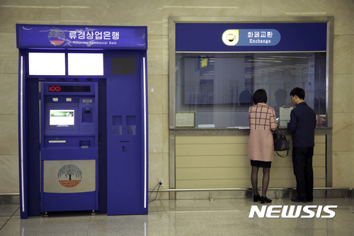 【평양=AP/뉴시스】2017년 4월 11일 평양의 순안공항 안에 설치된 류경상업은행 현금지급기가 작동하지 않아 현금을 찾을 수 없게 된 남녀가 환전 창구 앞에서 서로 의논하고 있는 모습. 이 현금지급기는 북한 화폐를 내놓지 않고 작동을 멈췄으며 이는 최근 중국의 새로운 북한 제재의 일환으로 서비스가 중단된 것으로 알려졌다. 2017.04.24