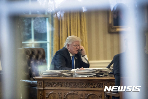DAY 9 - In this Jan. 28, 2017, file photo, President Donald Trump speaks on the phone with German Chancellor Angela Merkel in the Oval Office at the White House in Washington. (AP Photo/Andrew Harnik, File)
